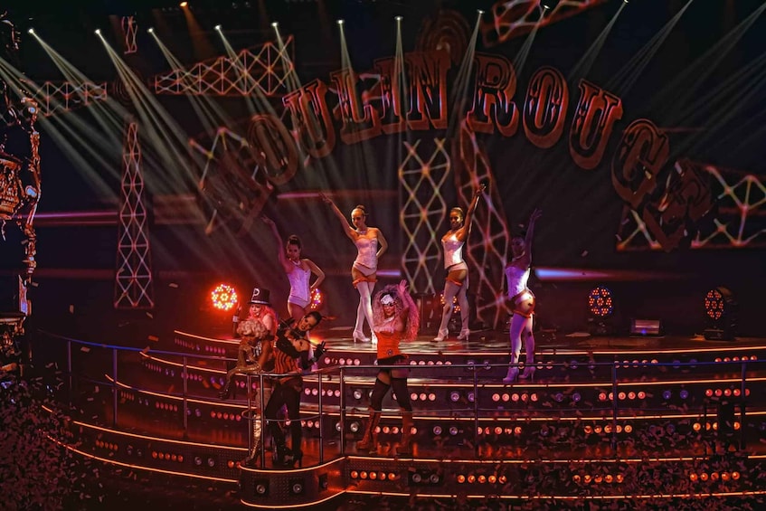 A stage with performers in costumes, a large illuminated sign, and a crowd of spectators. 1
