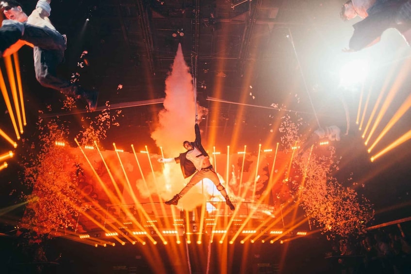 A person performing on stage with dynamic lighting and smoke effects. 3