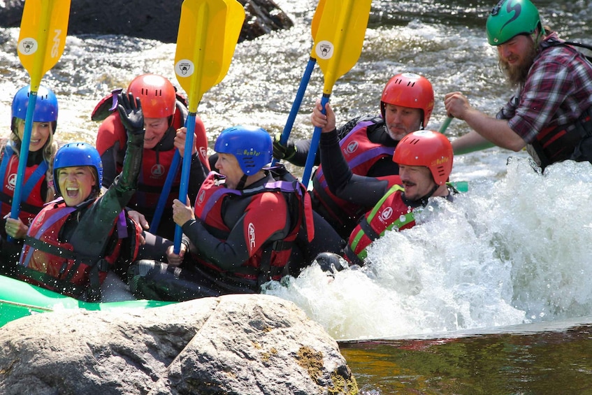 A group of people in a white raft navigating a river with rapids. 1