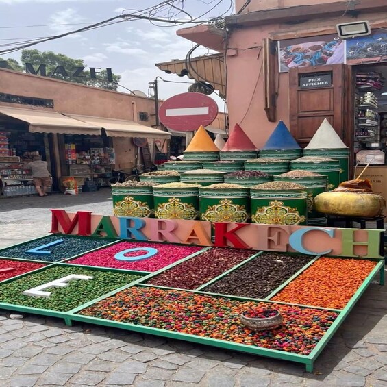 A Marrakesh market stall with colorful spices and a sign spelling 'MARRAKECH.' 2