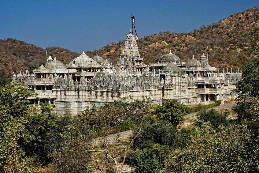 A large, intricately designed temple complex with multiple domes and spires, surrounded by lush greenery and hills. 2