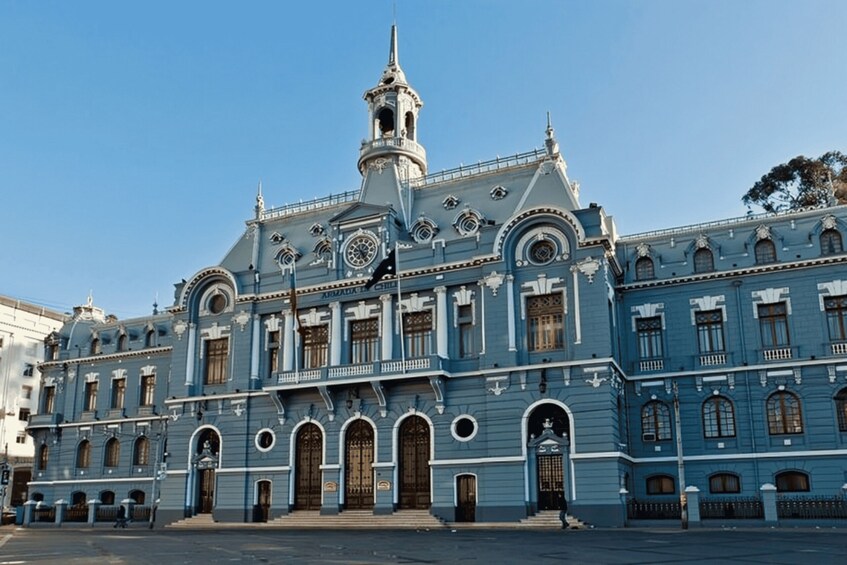 A large blue building with a clock tower, arched windows, and a central entrance. 4