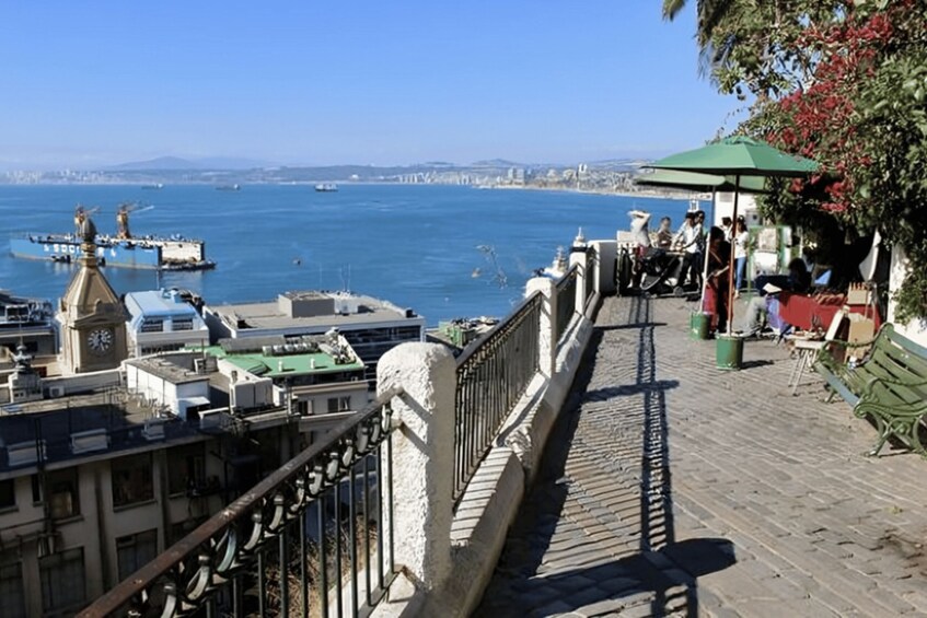 A coastal promenade with a view of the sea, boats, and a clock tower. 5