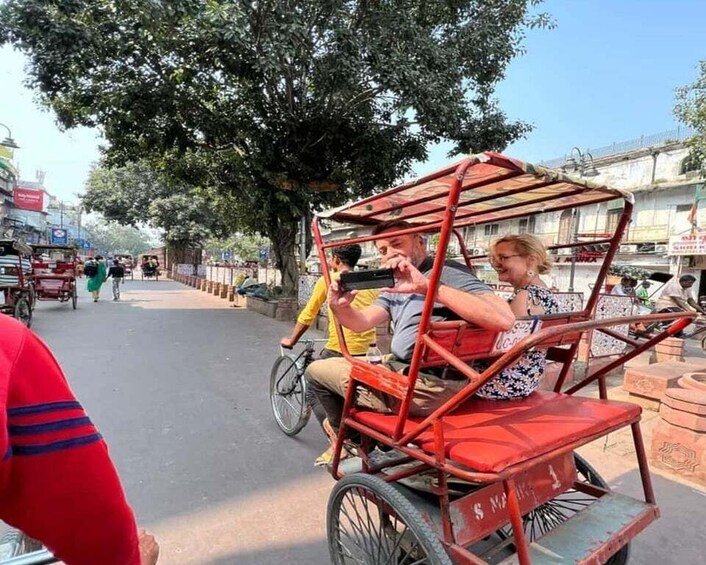 A rickshaw with passengers, a tree-lined street, and buildings in the background. 4