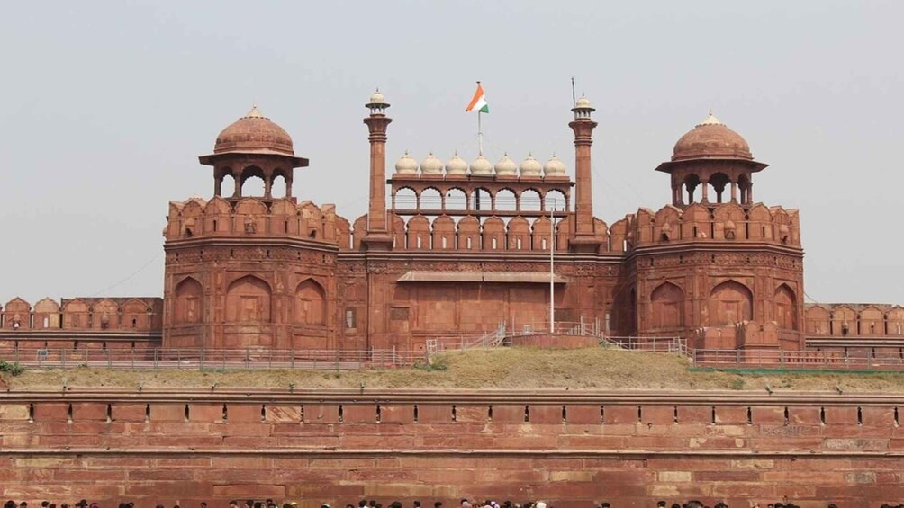 A large, historic building with domed towers and a central archway, featuring the Indian flag. 2