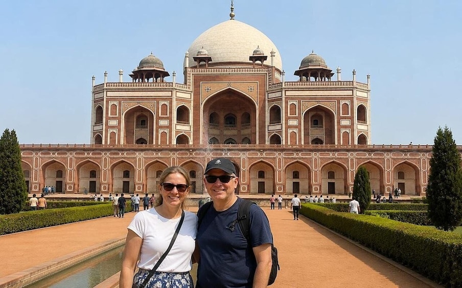 A large historical building with domes and arches, surrounded by a well-maintained garden. 1