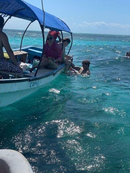 A boat with people on board and others swimming in the water. 3