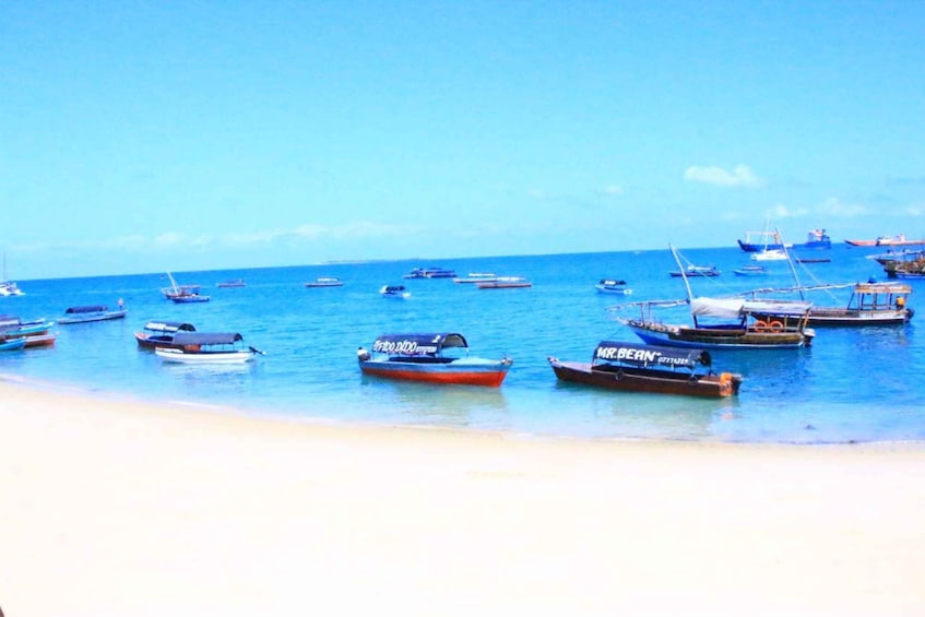 A beach with several boats anchored in the water. 1