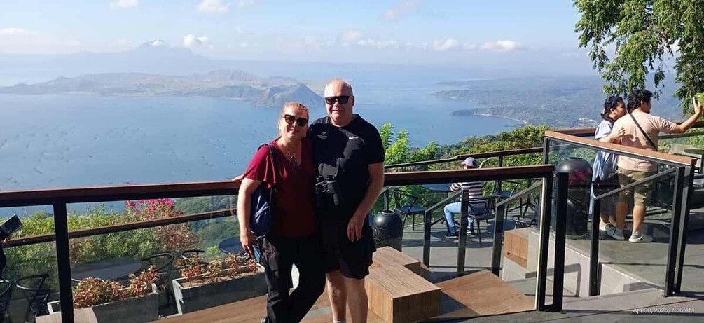 Two people standing on a balcony overlooking a body of water and distant land. 3
