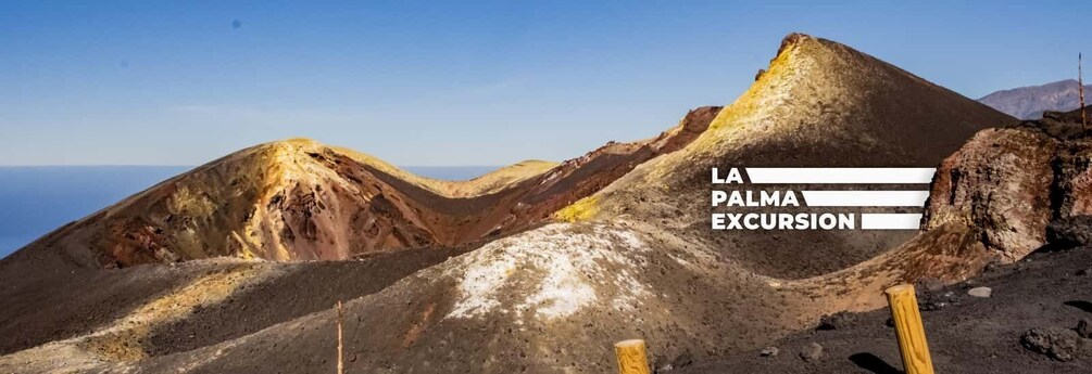 A volcanic landscape with a wooden post and the text "LA PALMA EXCURSION". 1