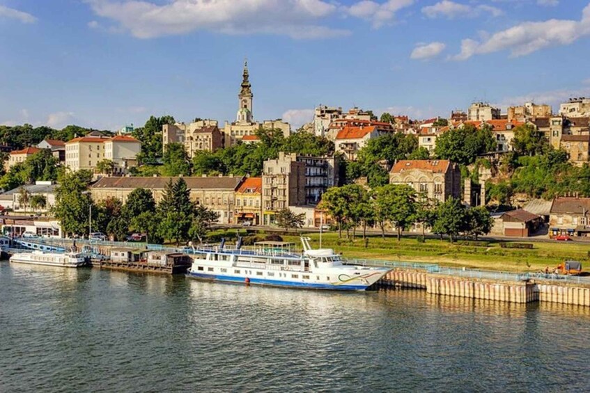 A river with boats, a prominent church with a tall tower, and a densely built hillside with various buildings. 3