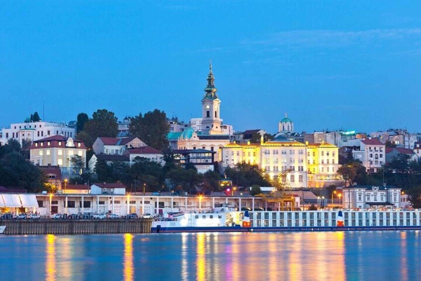 A cityscape at dusk with a prominent church tower reflecting on the water. 5