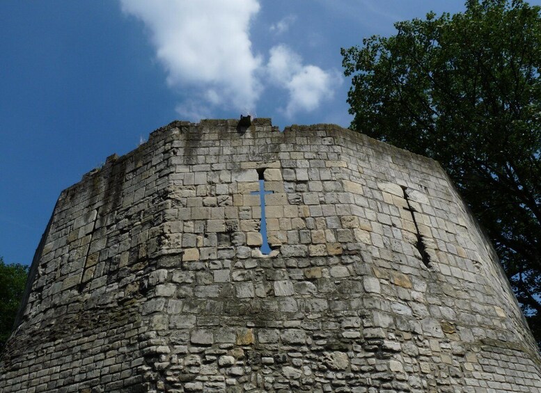 A stone tower with a blue vertical line marking, surrounded by trees and a clear sky. 5