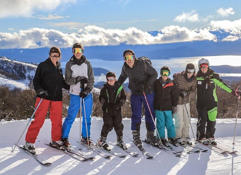 A group of skiers on a snowy slope with a mountain and lake in the background. 2