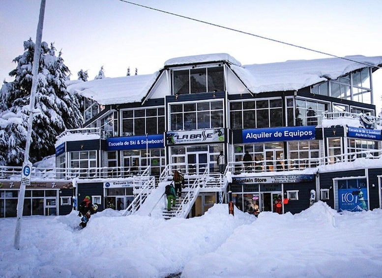 A ski resort building with signage for 'Escuela de Ski & Snowboard' and 'Alquiler de Equipos'. 5