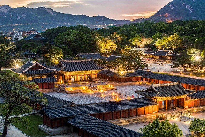 A traditional Korean palace complex with multiple buildings, a courtyard, and surrounding mountains. 1