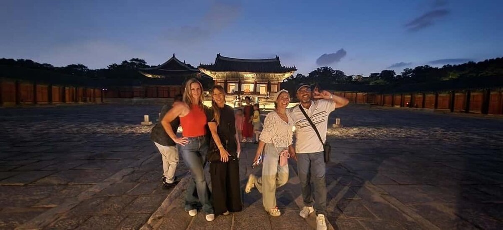 A group of people standing in front of a traditional building with a tiled roof. 4