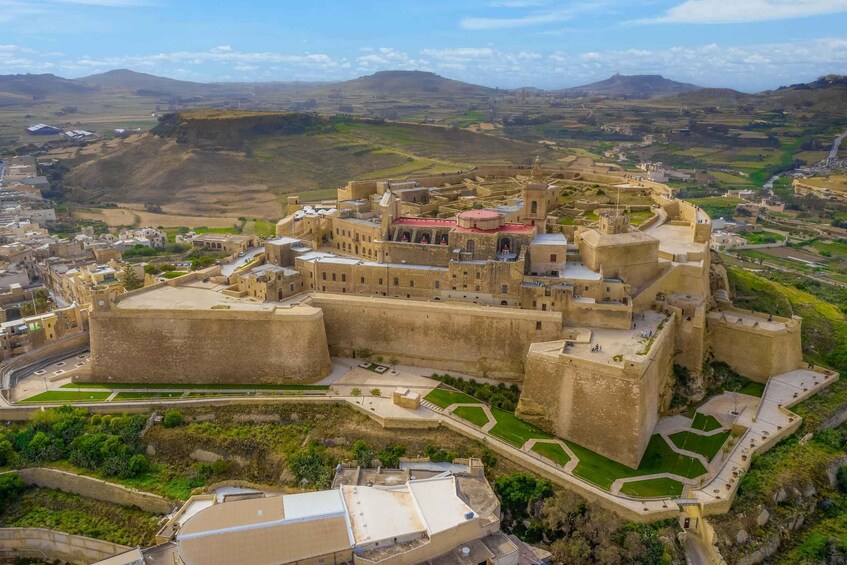 A fortified city with historic architecture, surrounded by hilly terrain. 5