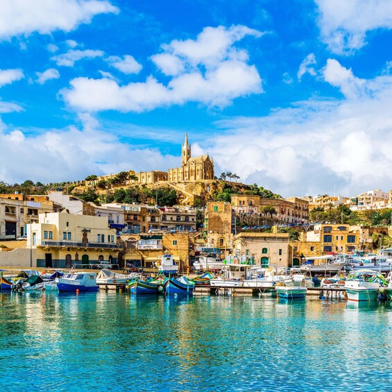 A coastal town with a prominent church on a hill, colorful boats docked in the harbor, and a clear blue sky. 2