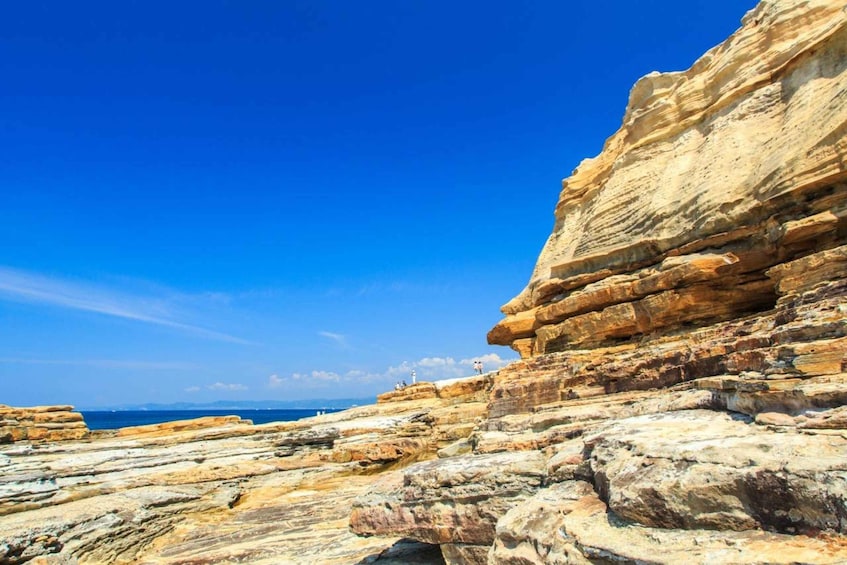 Layered rock formations along a coastline with a clear blue sky. 5