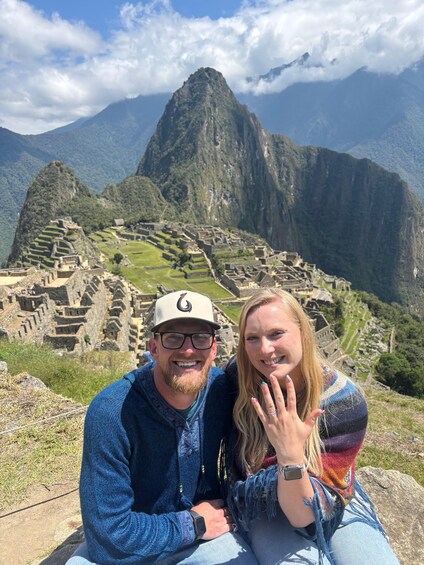 A couple sitting in front of Machu Picchu with the mountain range in the background. 3