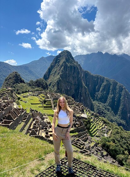A person standing on a viewing platform with Machu Picchu ruins in the background. 5