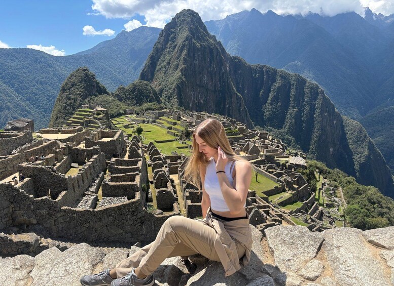A person sitting on a rock with Machu Picchu ruins in the background. 1