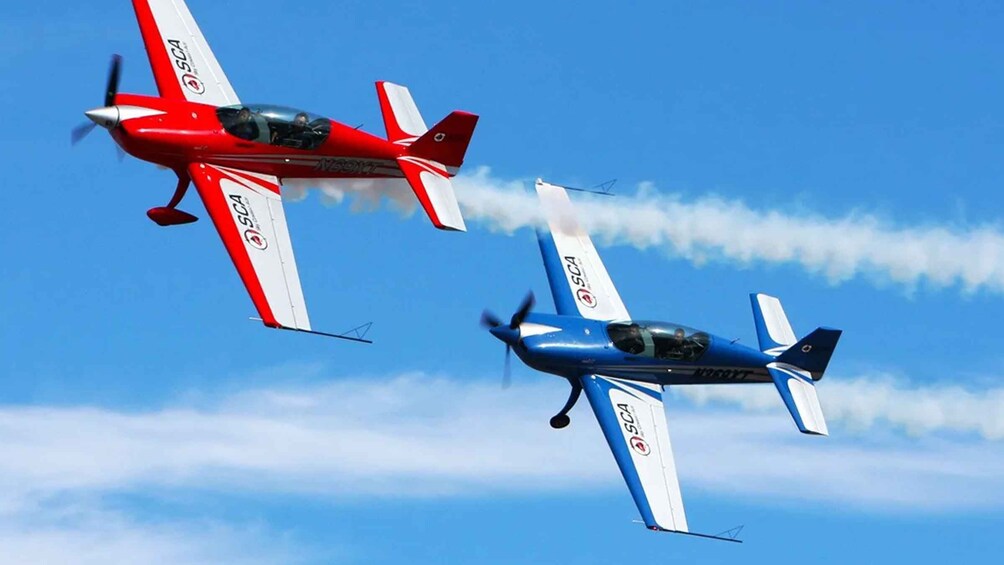 Two small aircraft flying in formation with smoke trails. 1