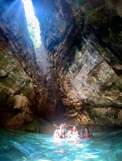 A group of people in a natural cave with clear water, surrounded by rocky walls. 4