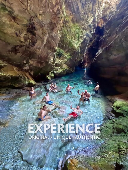 A group of people swimming in a natural pool surrounded by rocky cliffs. 1
