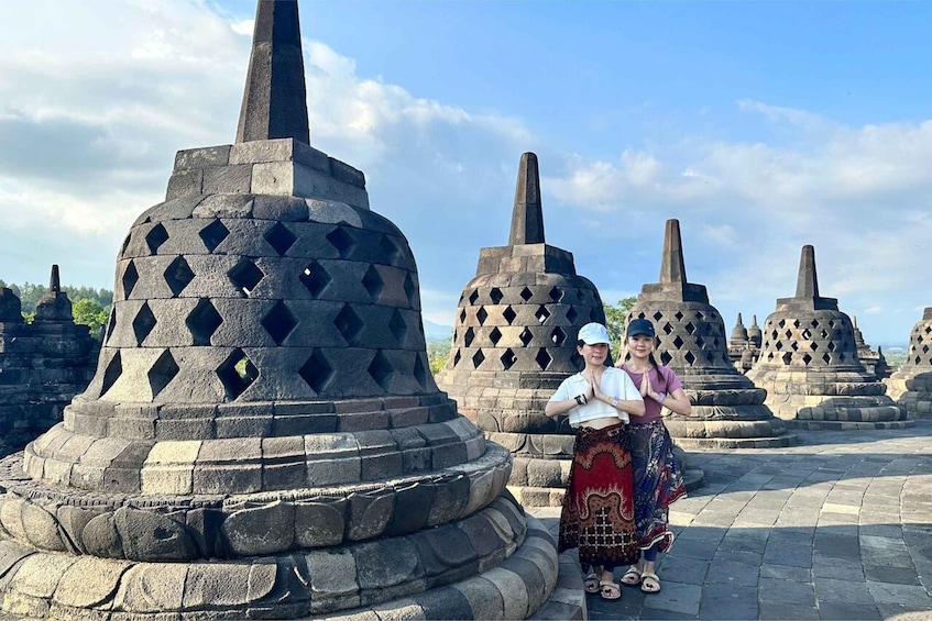 A person standing in front of a stone structure with a pointed top and diamond-shaped openings. 1