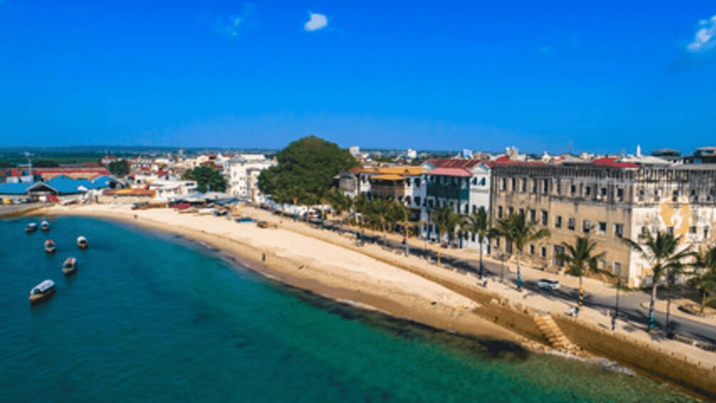 A coastal town with a sandy beach, clear blue water, and buildings along the shore. 4
