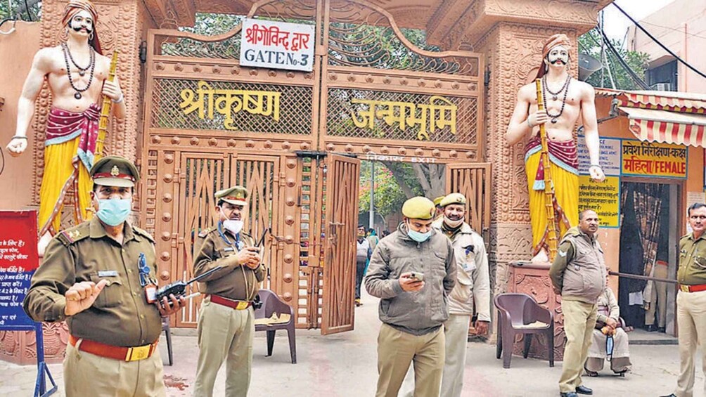A guarded temple entrance with statues and security personnel. 5