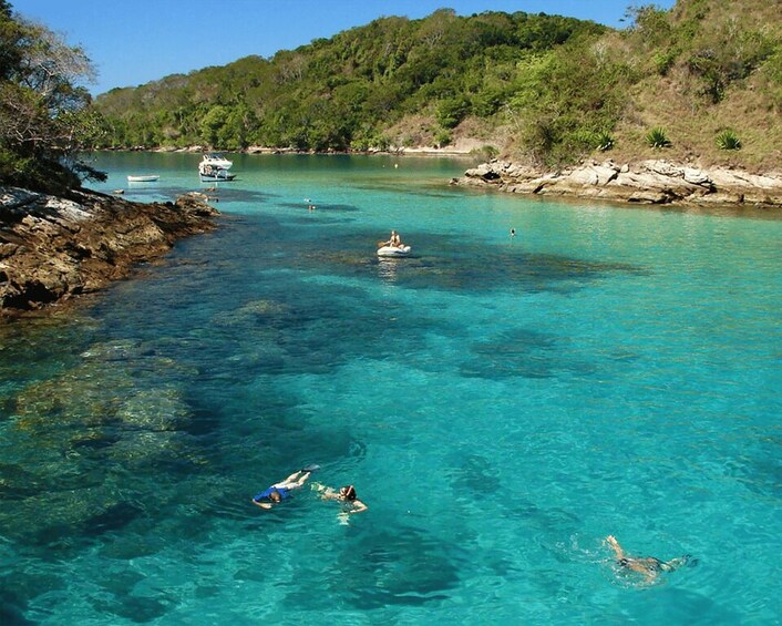 A clear turquoise sea with swimmers and a boat. 2