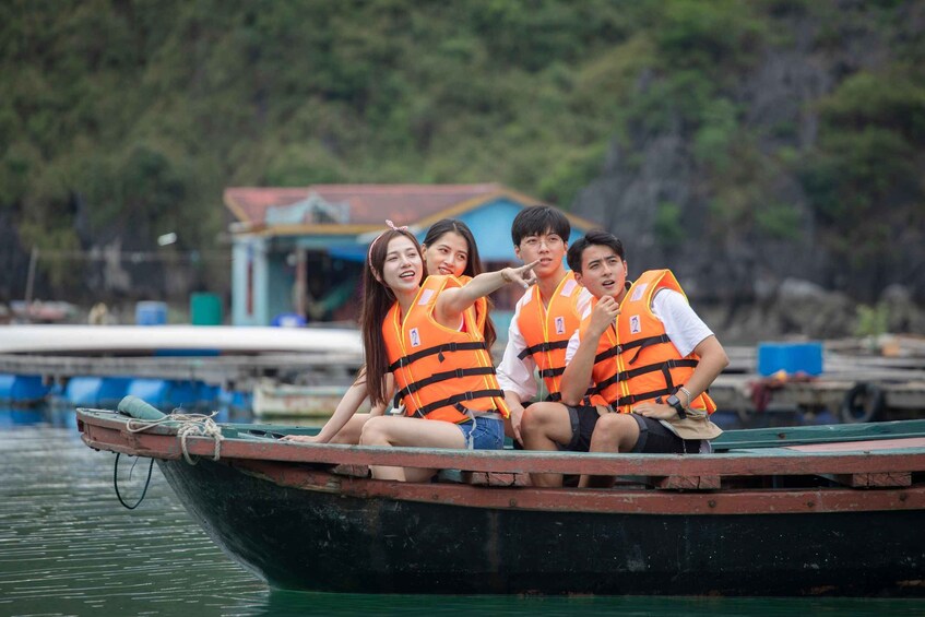Four people on a boat wearing orange life jackets. 2