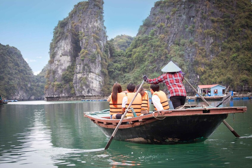 A boat with passengers wearing life jackets, a guide in a conical hat, and a rocky landscape in the background. 1