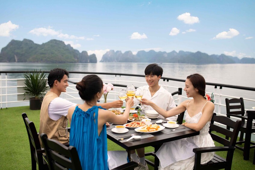 A group of people dining at an outdoor table with a scenic lake and mountains in the background. 4
