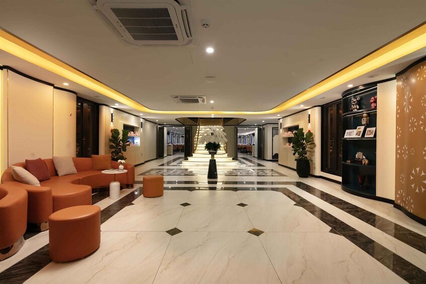A modern lobby with a central floral arrangement, orange seating, and a patterned floor. 4