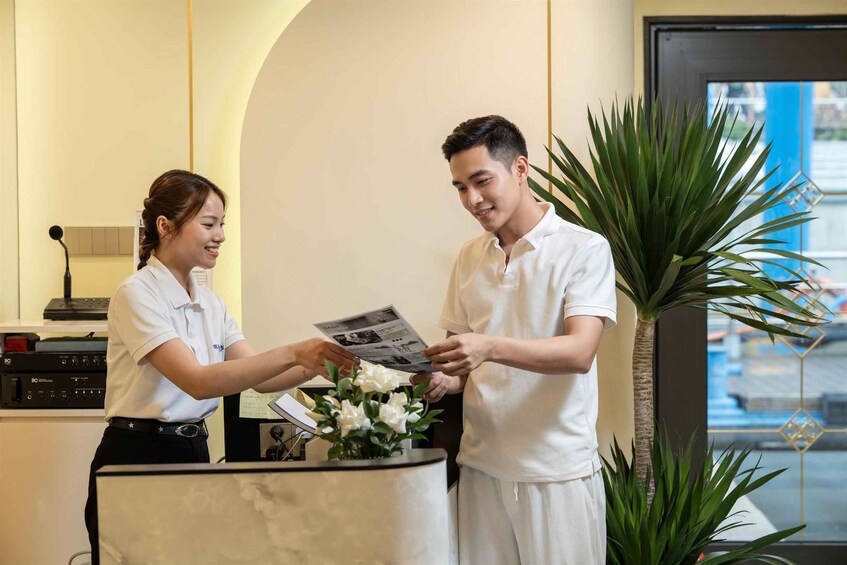 A reception desk with a receptionist handing a brochure to a guest. 3