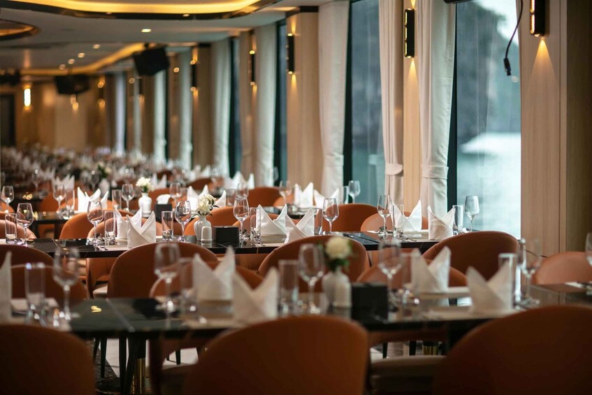 A restaurant with tables set for dining, chairs, and a view of the water outside. 2