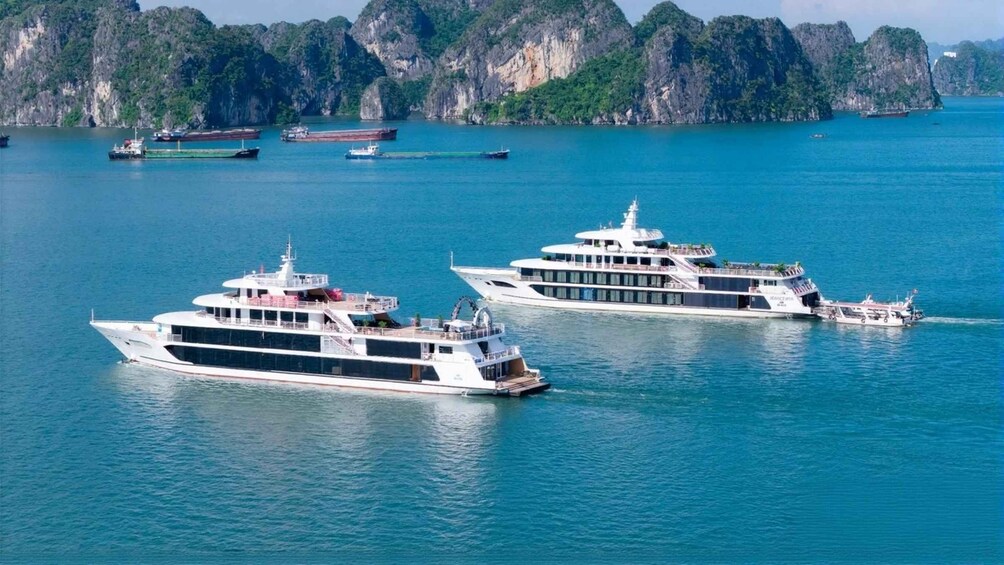 Three large white yachts on calm blue waters with rocky cliffs in the background. 1
