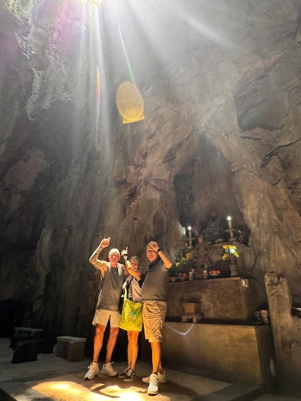 Three people standing in a cave with a shrine in the background. 3