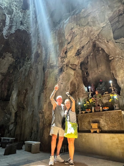 Two people standing in a cave with a waterfall. 4