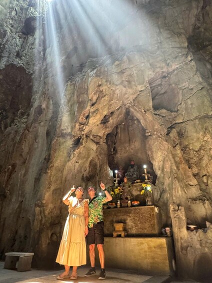 A cave with a rock formation and a shrine with statues and flowers. 2