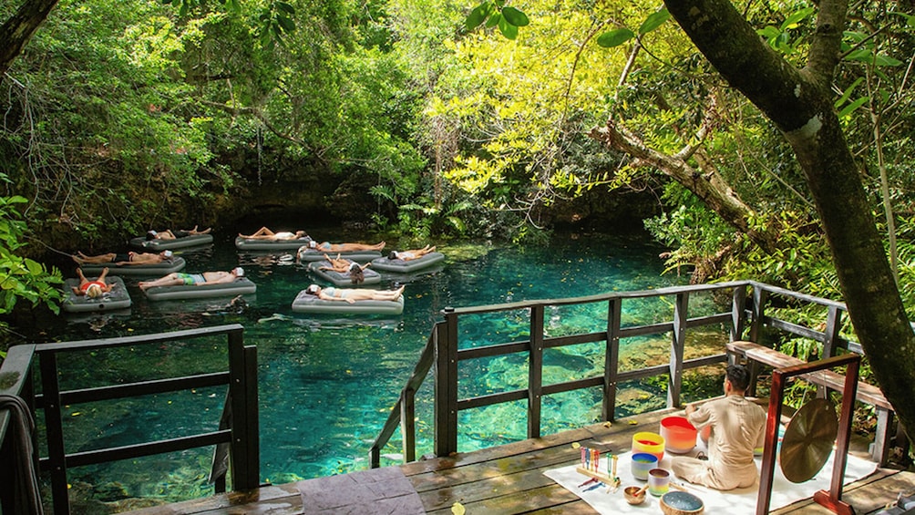 People floating on inflatable rafts in a clear river surrounded by dense forest. 4