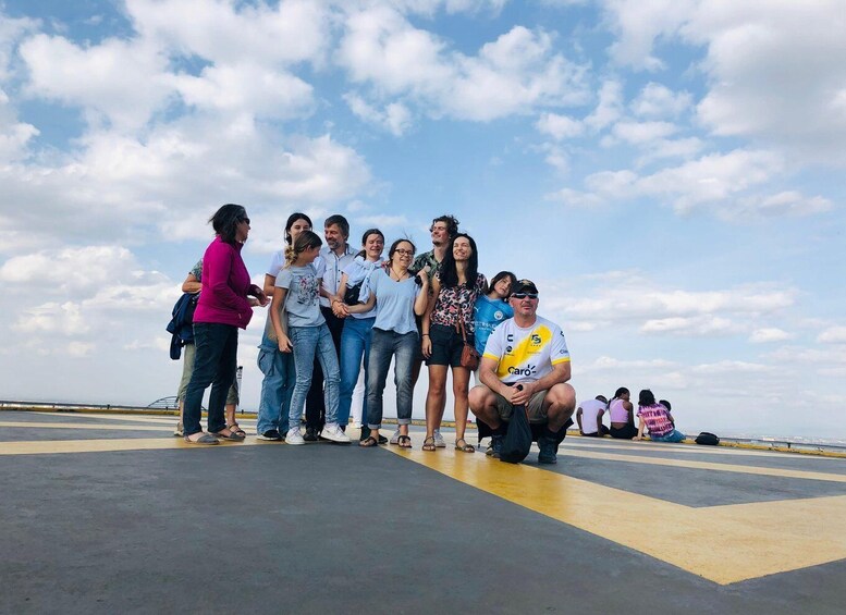 A group of people standing and sitting on a platform with a clear sky in the background. 2