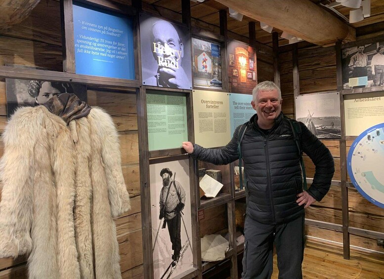 A man standing next to a display with historical information and a fur coat. 3