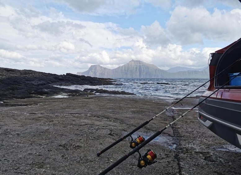 A rocky beach with fishing rods and a car. 3