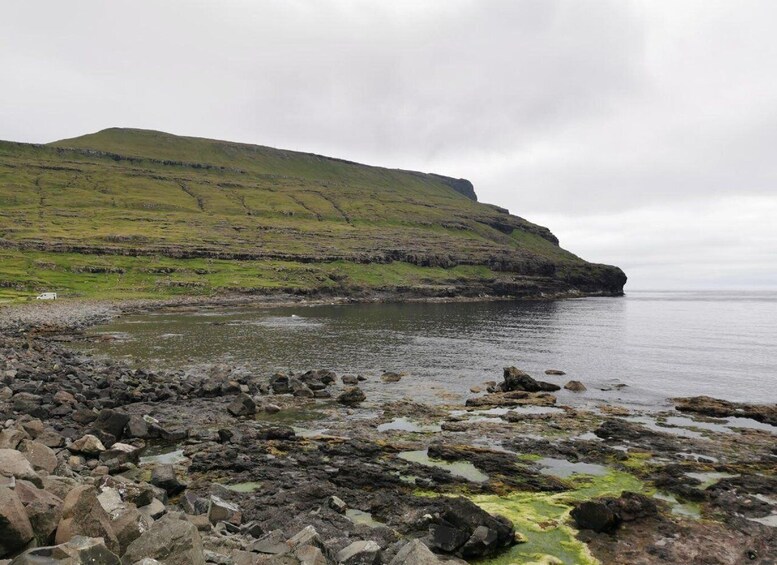 A rocky shoreline with a grassy hill in the background. 4