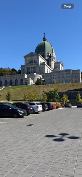 A large building with a green dome and classical architecture, surrounded by a parking lot and trees. 3